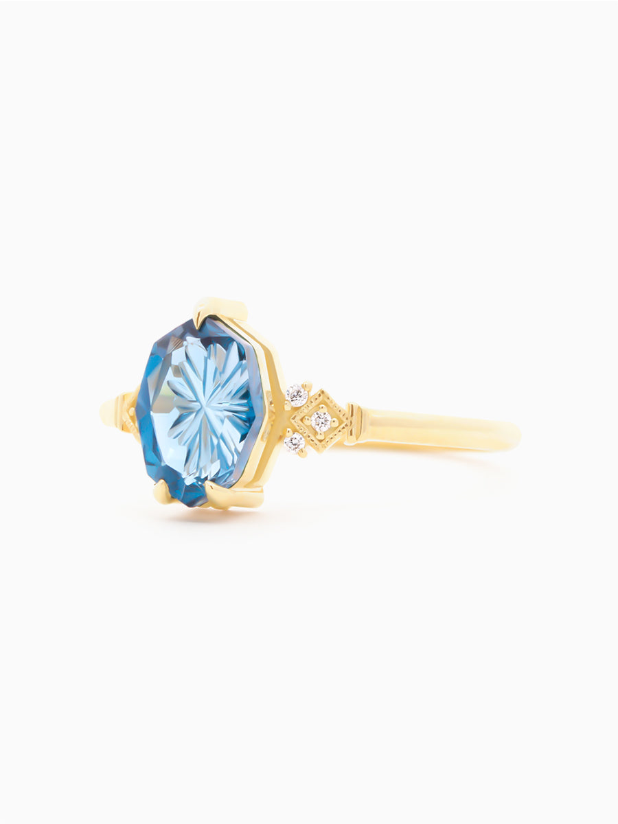 Gold ring with a blue starbrite sapphire on a white background. side view