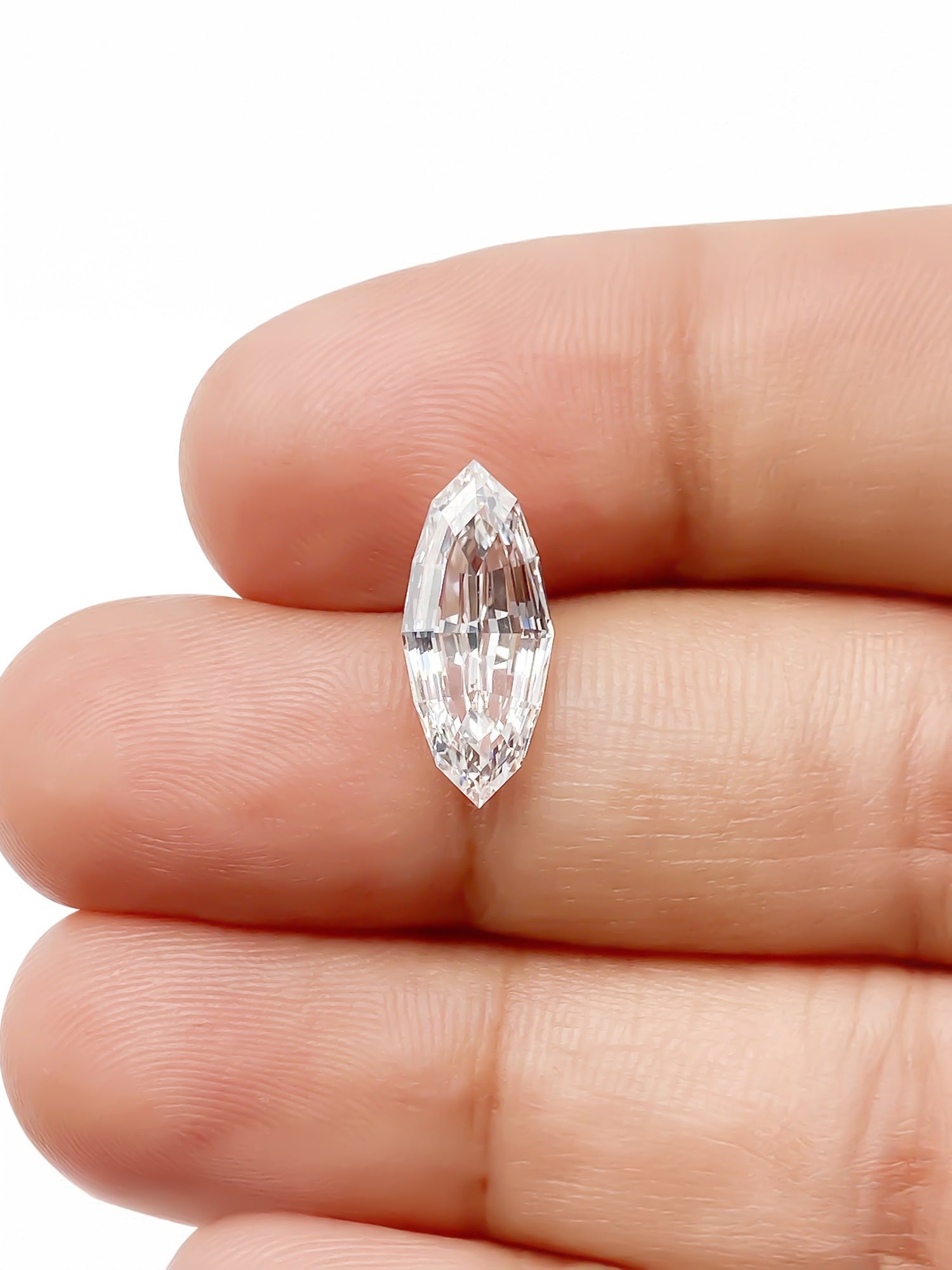 Marquise-shaped diamond held between fingers against a white background for scale
