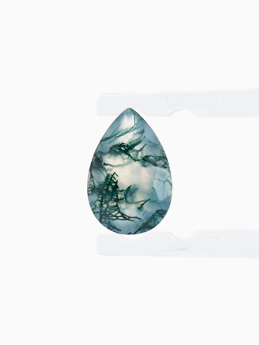 blue-green moss agate pear with dendritic inclusions held by tweezers to show light shining through