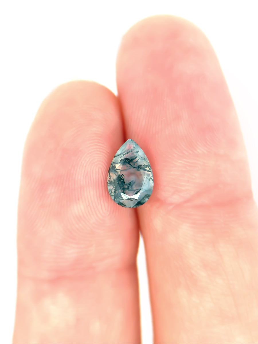 blue-green moss agate pear with dendritic inclusions on finger to show scale