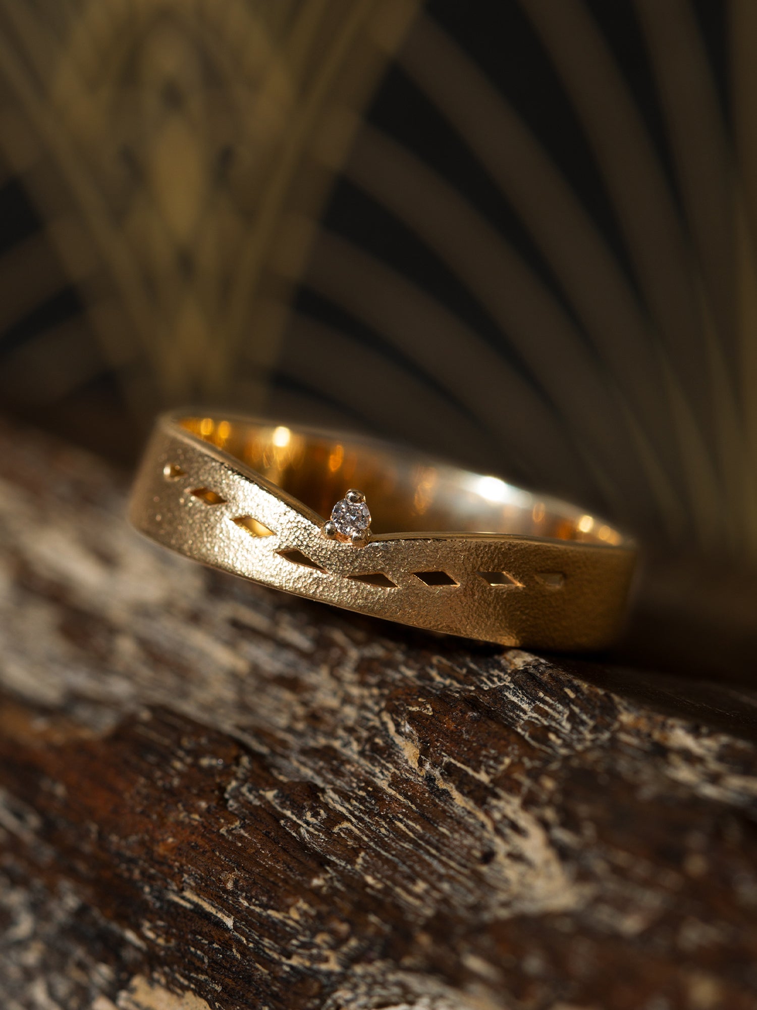 Gold ring with a diamond on a textured wooden surface