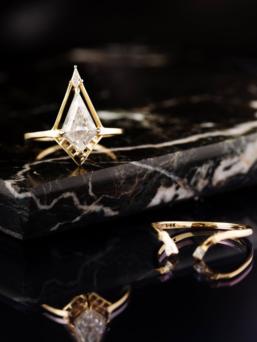 Gold Kite Deco ring with a diamond on a black marble surface