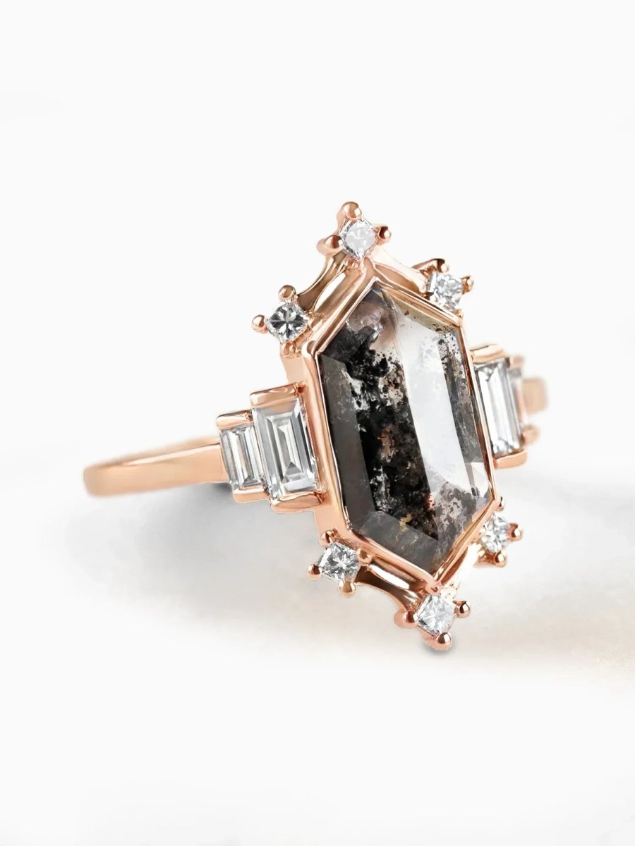 Rose gold ring with a large central gemstone and smaller diamonds on a white background