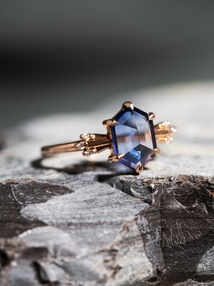 Rose gold ring with a blue gemstone on a textured stone surface