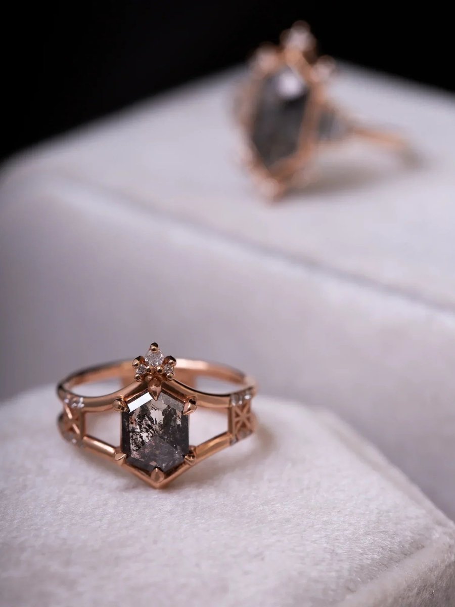 Rose gold ring with a dark gemstone on a white surface