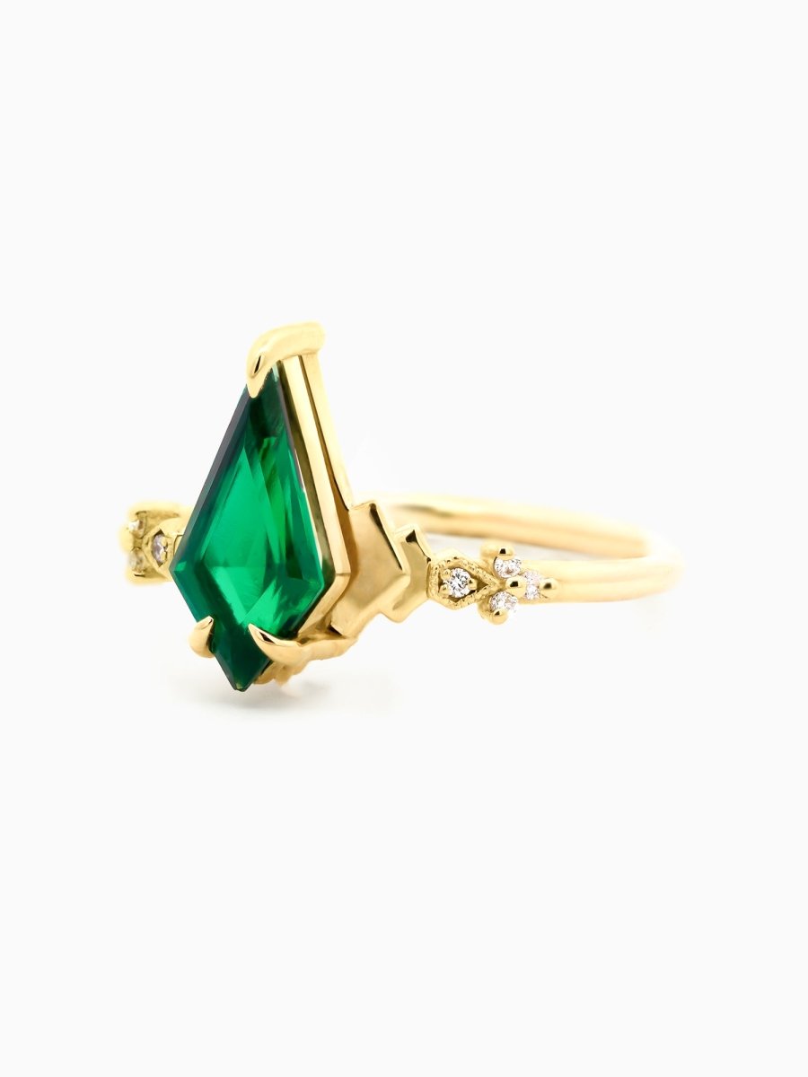 side of minimalist art deco engagement ring with emerald kite, stepped chevron shoulders, milgrain accents