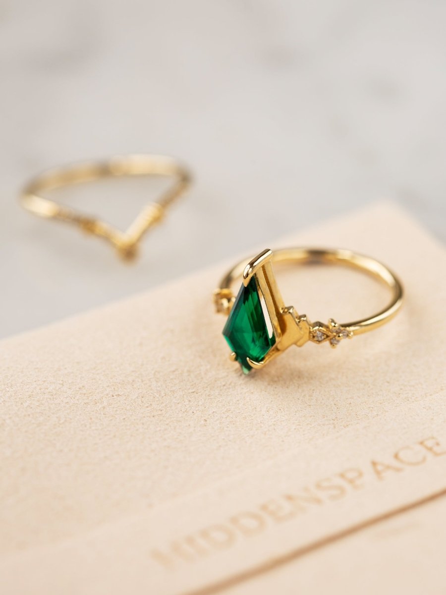 Gold ring with a green gemstone on a beige card with 'Hobbspace' branding.