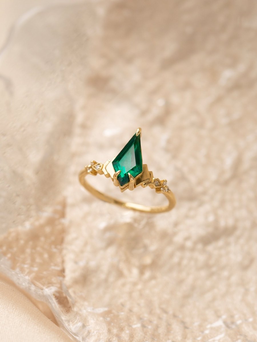 Gold ring with a green gemstone on a textured beige background