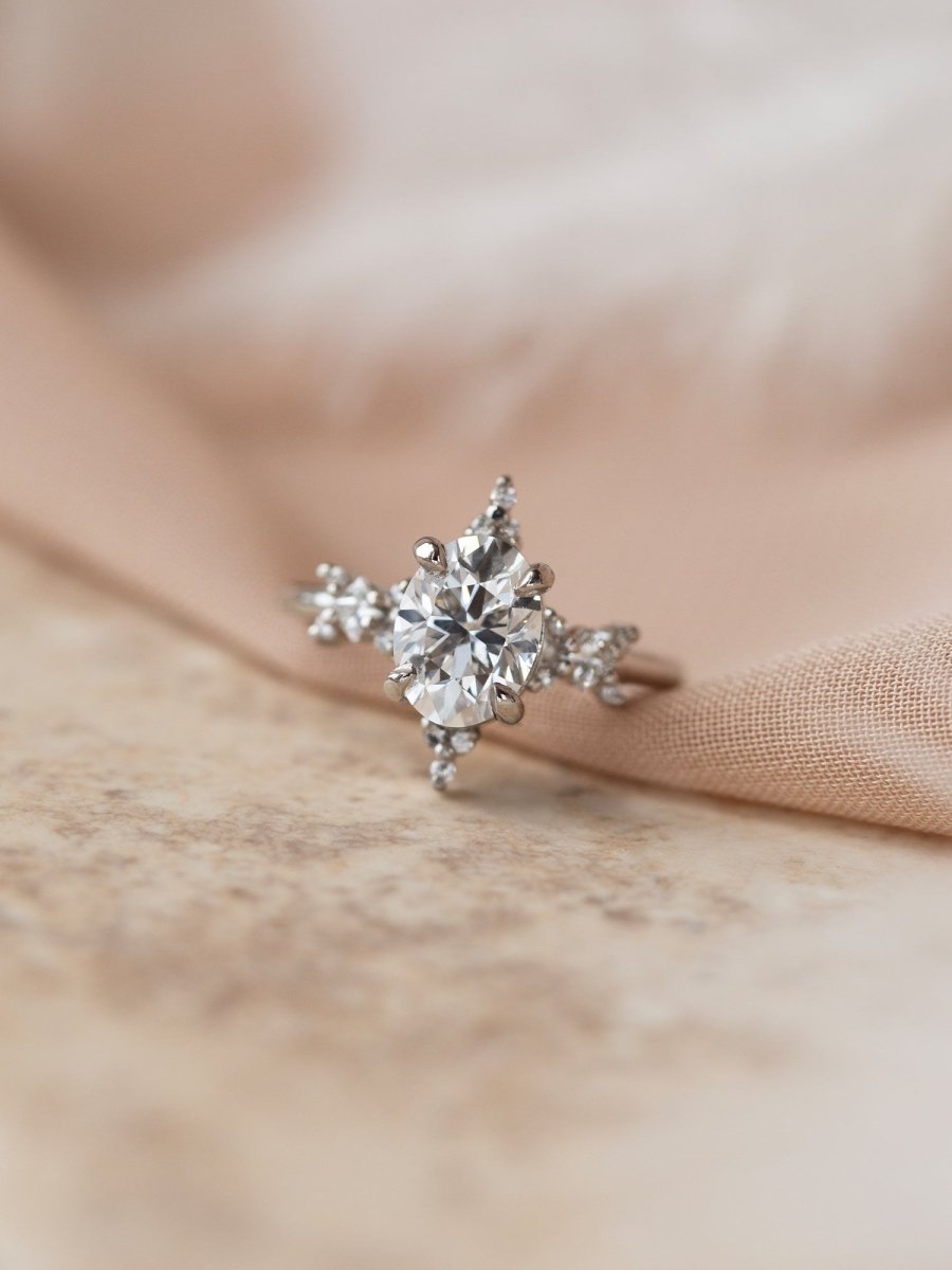Silver snowflake-shaped earring on a soft beige fabric background