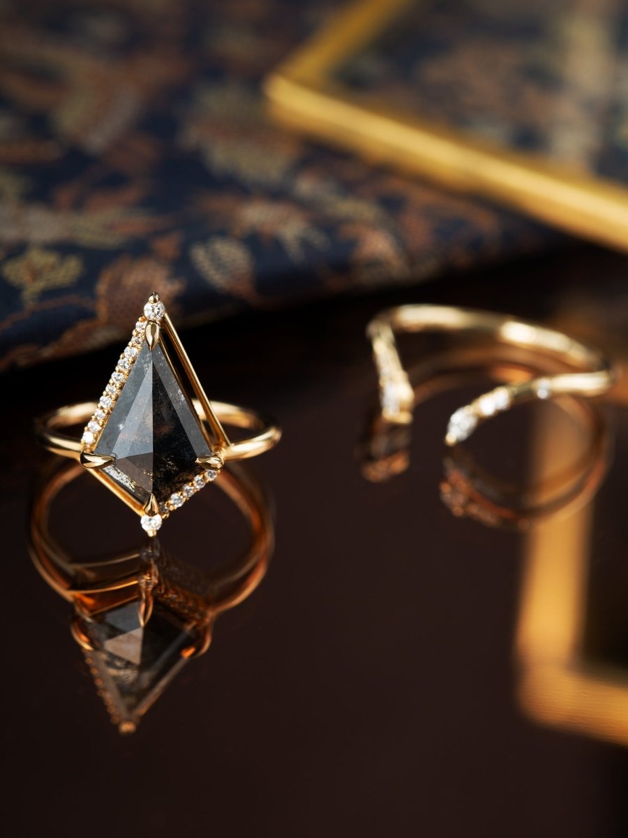 Gold ring with a triangular gemstone on a reflective surface
