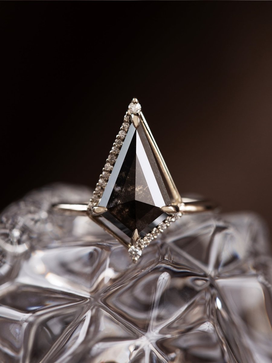 Triangular diamond ring with gold setting on a textured surface