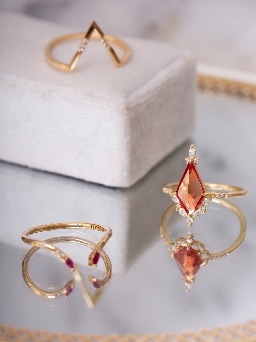 Gold rings with red gemstones on a light gray surface