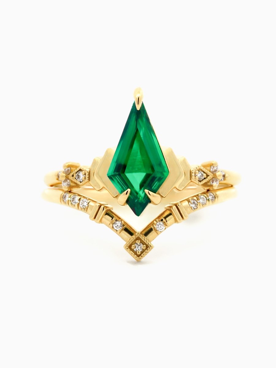 Face of Art Deco engagement ring with kite emerald, stepped chevron shoulders, milgrain accents, and chevron band