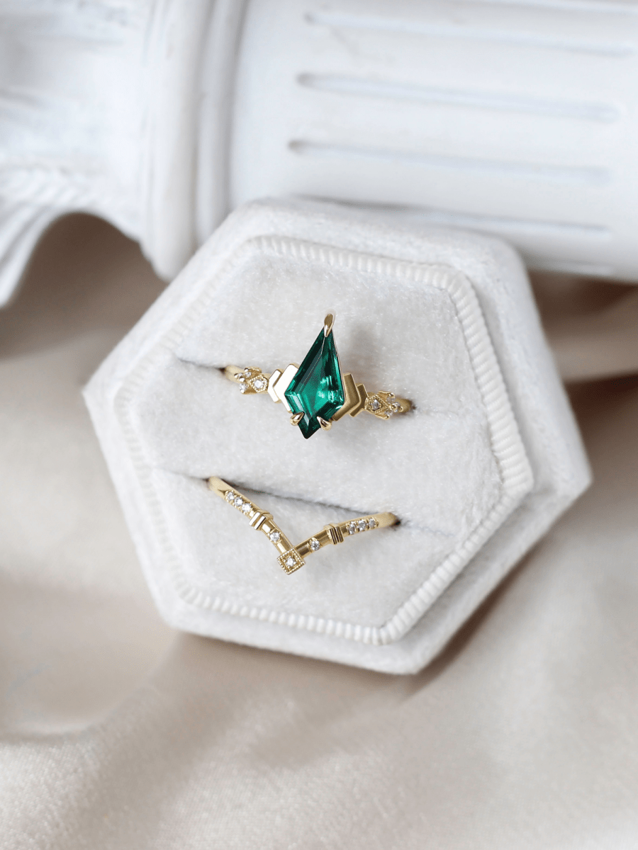 Art Deco ring with chevron band in white hexagonal box, set against a white column and soft beige satin for a sophisticated presentation
