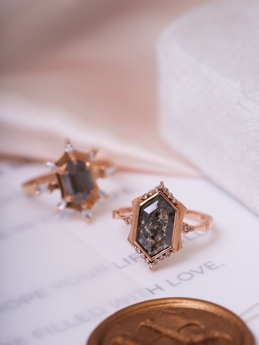 Rose gold ring with a dark gemstone on a white surface