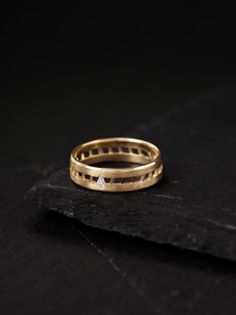 Gold ring with a small diamond on a dark stone surface
