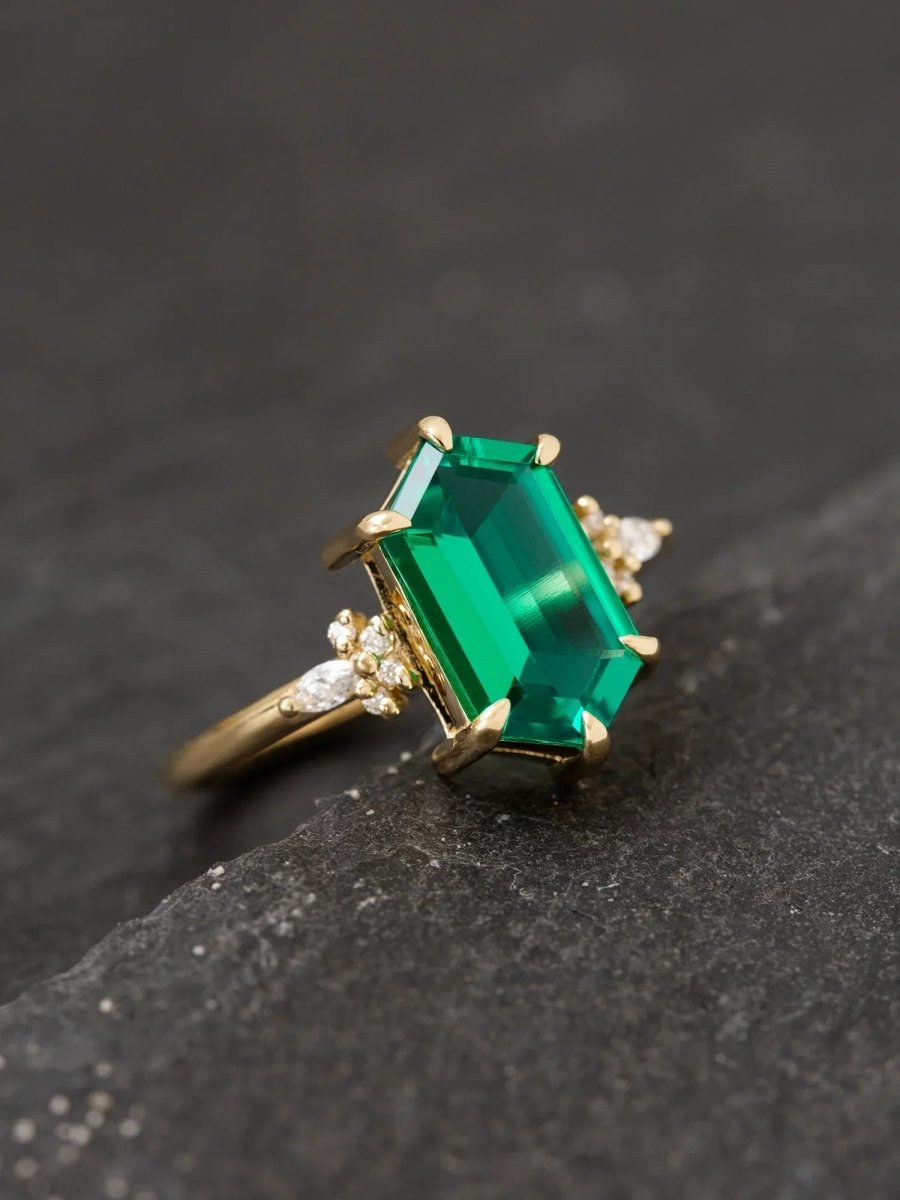 Gold ring with a large emerald green gemstone on a dark background