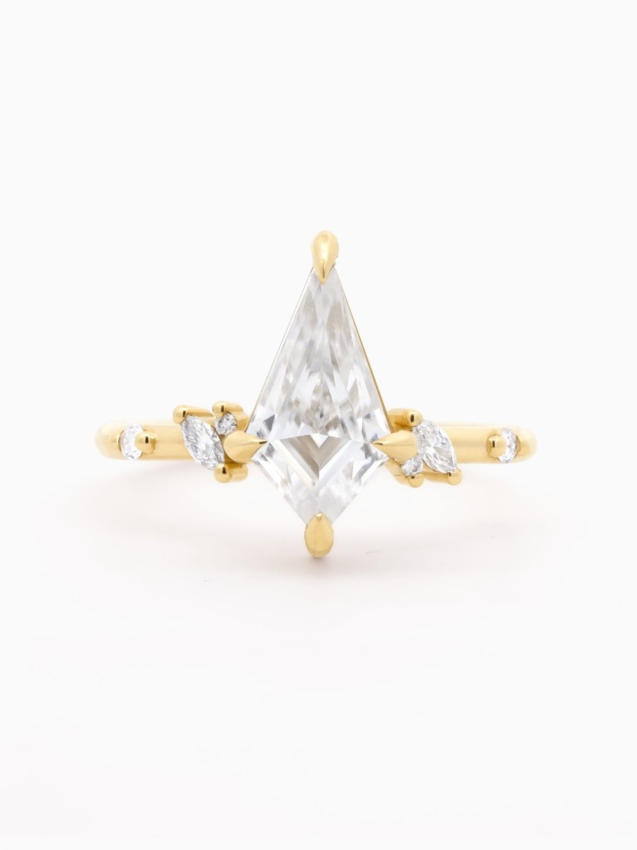 Face view of ring with kite-cut Moissanite above gold base framed by asymmetrical diamond clusters