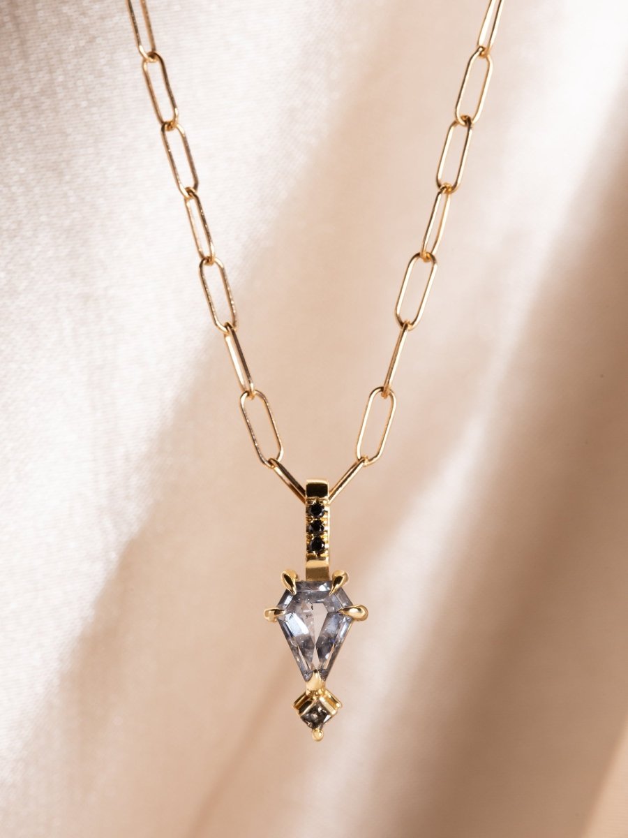 Gold necklace with a clear pendant on a beige background