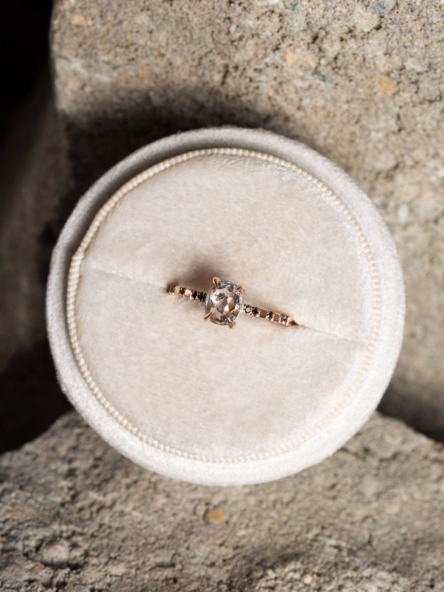 Diamond ring on a white cushion against a concrete background