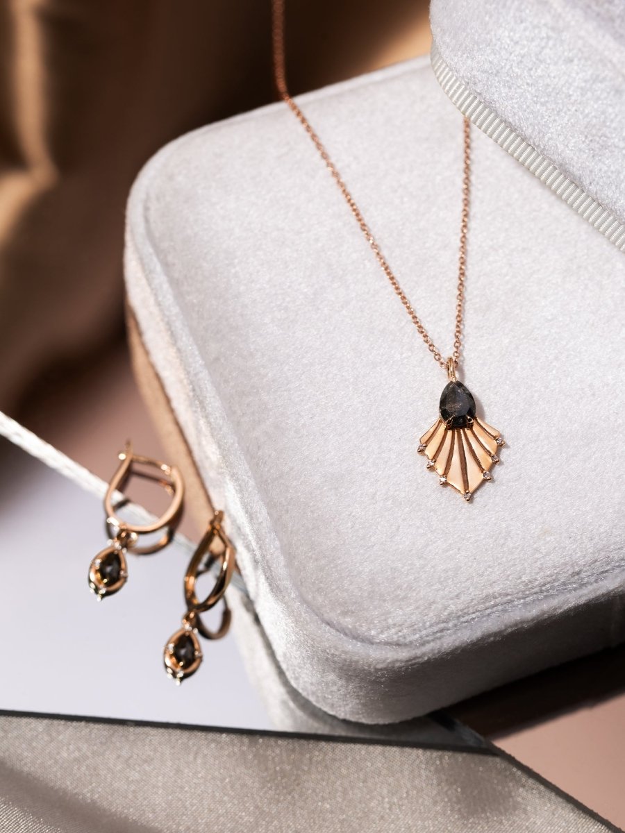 Rose gold necklace and earrings on a white jewelry box with a soft focus background