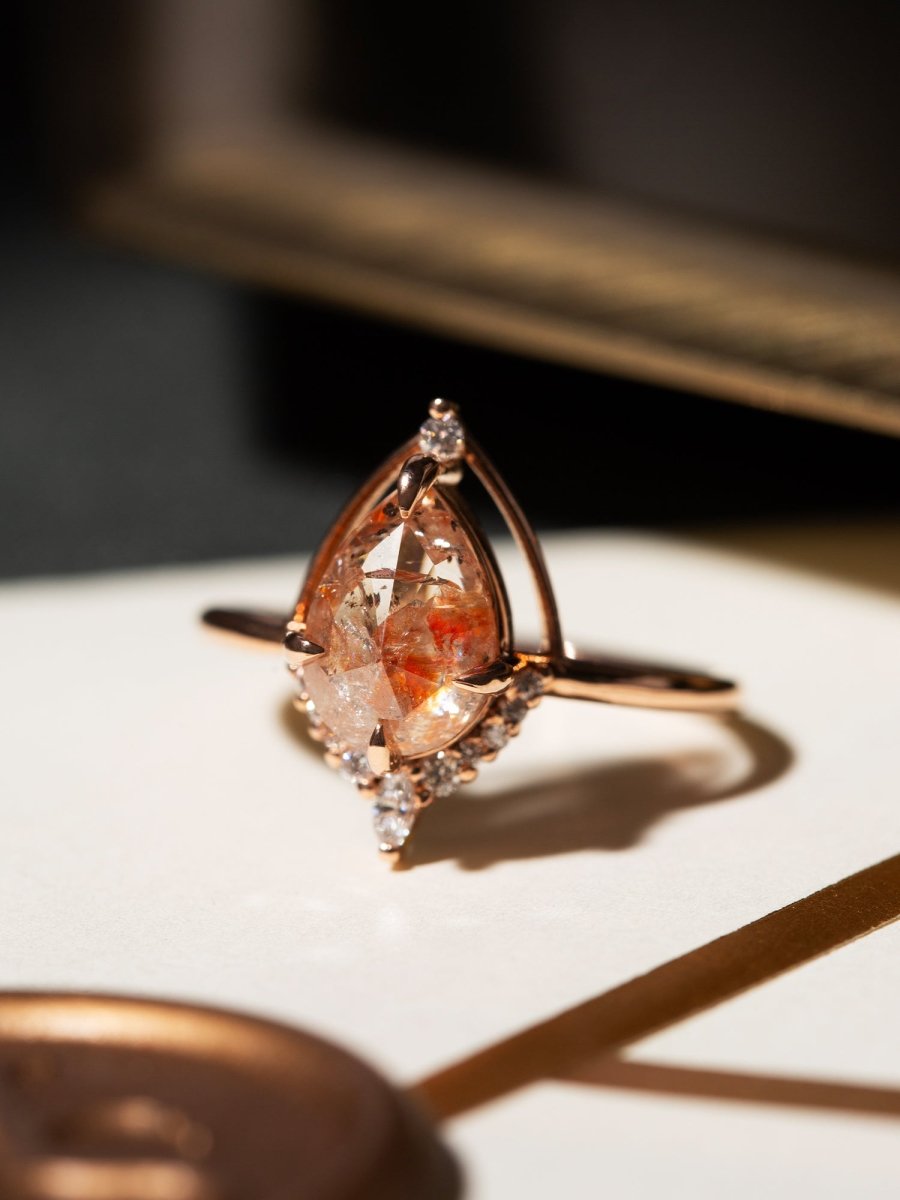 Rose gold ring with a large teardrop-shaped gemstone on a white surface.
