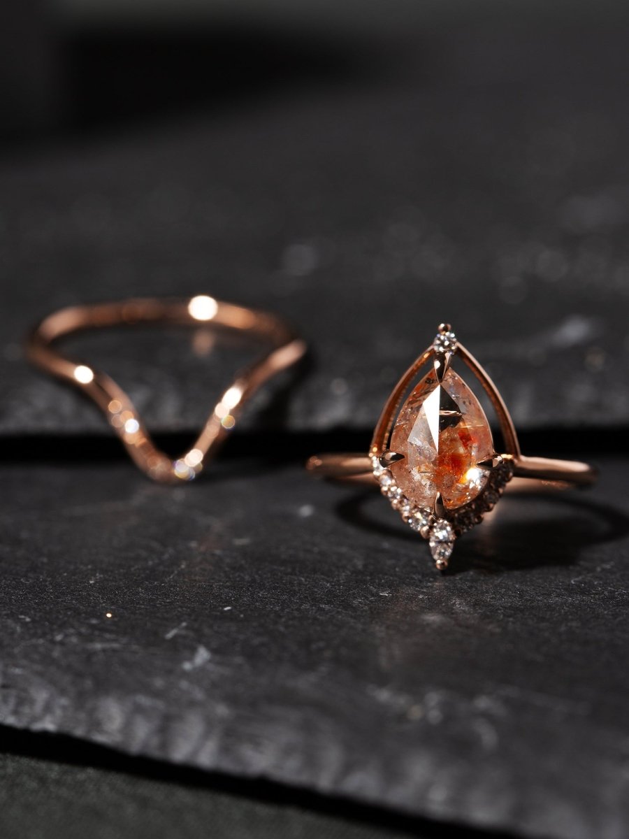 Rose gold ring with a pear-shaped gemstone on a dark surface