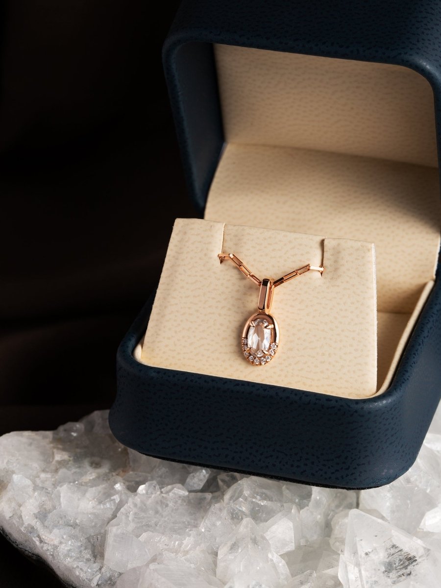 Rose gold necklace in a jewelry box on a dark surface with crystals below