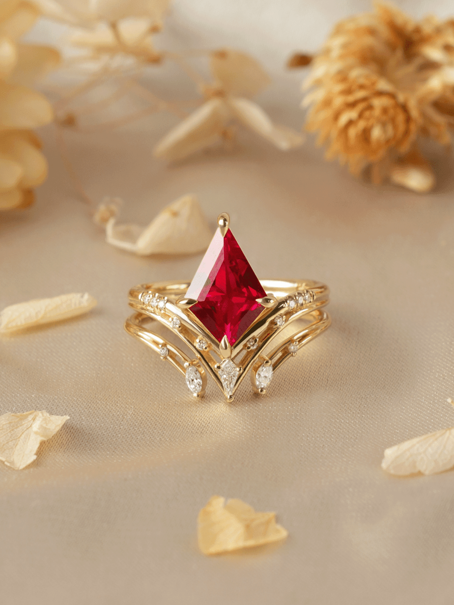 Gold ring with a red gemstone on a beige background with dried flowers