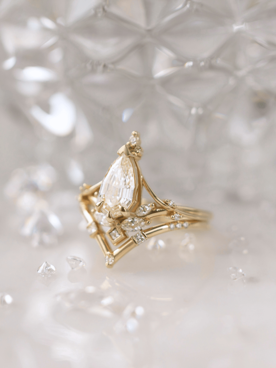 Art Nouveau-inspired split shank engagement ring with marquise diamond, and chevron contour band in front of glass