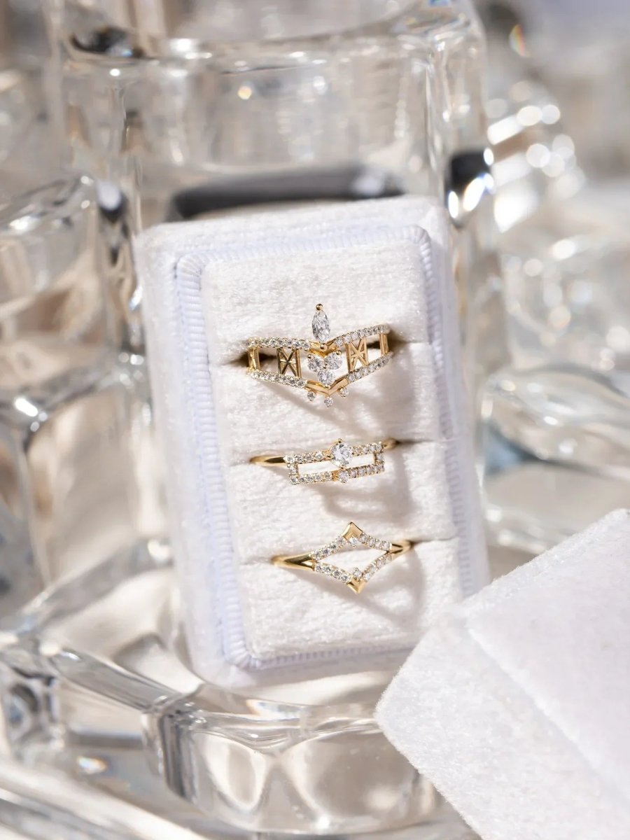 Gold rings with diamonds on a white jewelry box inside a clear glass display case.