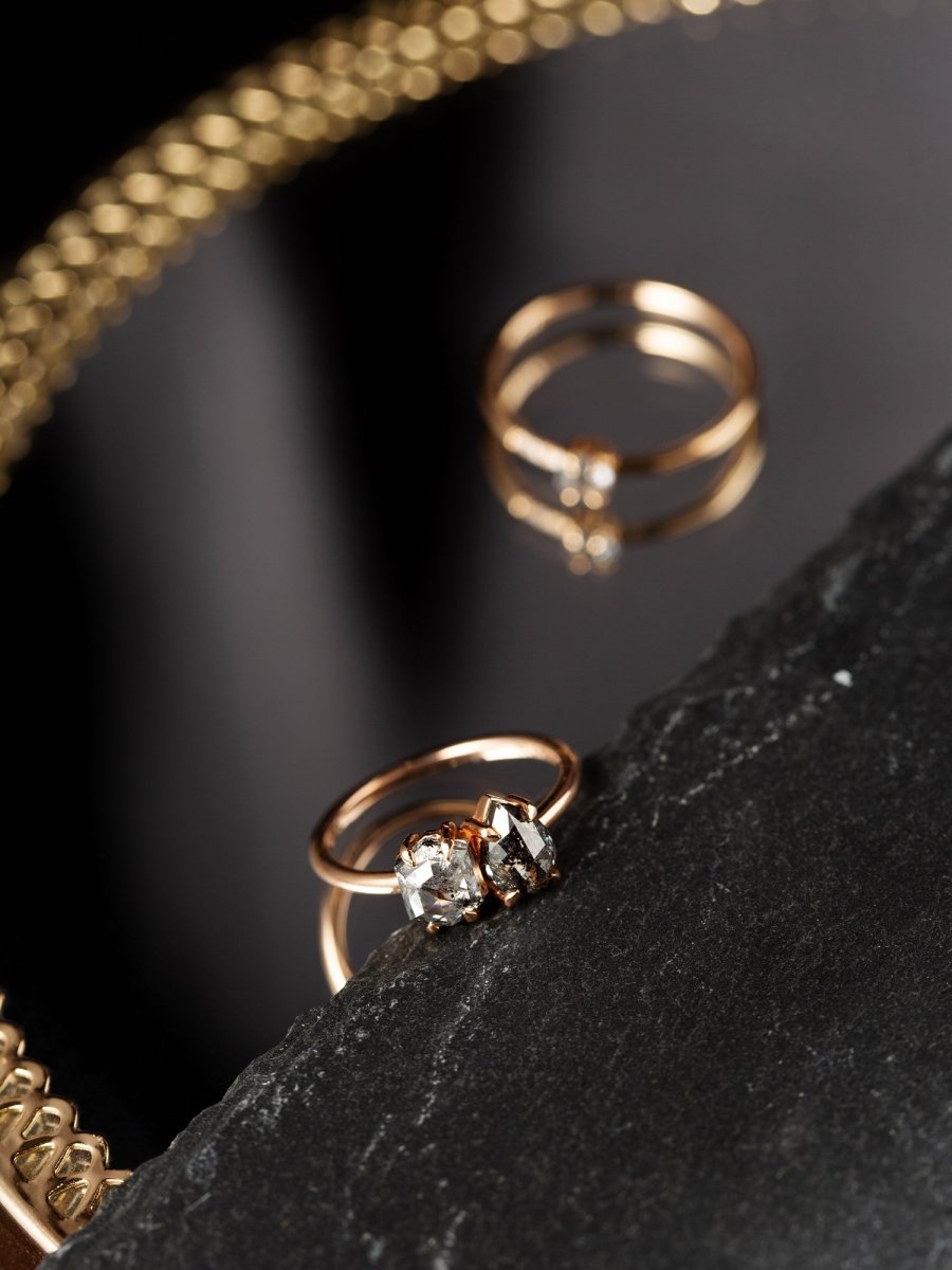 Two gold rings with diamond accents on a dark surface