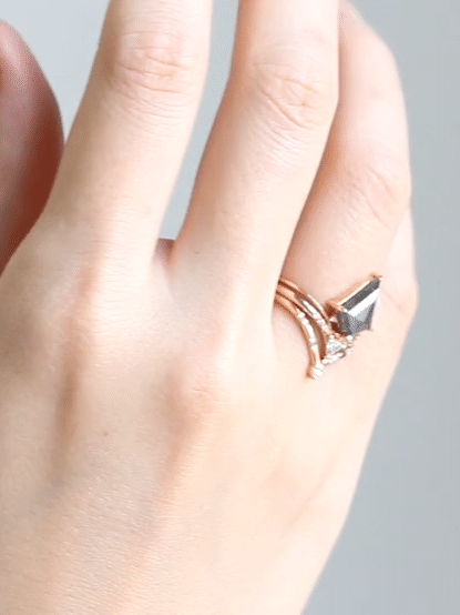 Minimalistic and art deco styled kite salt and pepper diamond engagement ring in 14k rose gold with a trilliant and round diamonds.