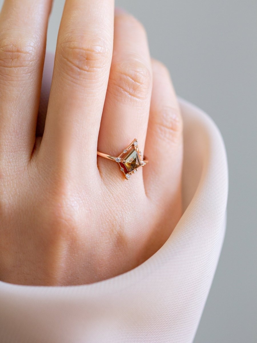 Minimal art deco styled kite shaped salt and pepper diamond engagement ring in 14k rose gold with smaller round diamonds on model's hand.