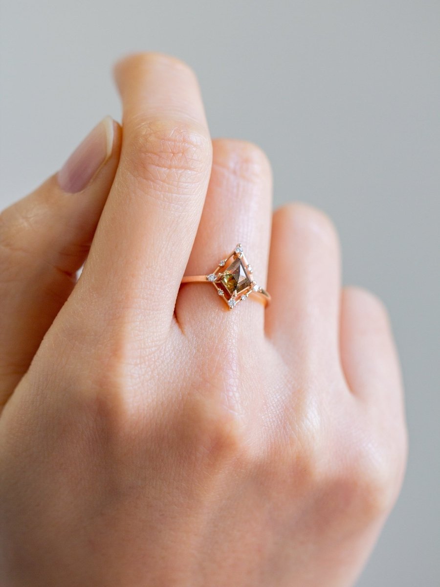 Minimal art deco styled kite shaped salt and pepper diamond engagement ring in 14k rose gold with smaller round diamonds on model's hand.