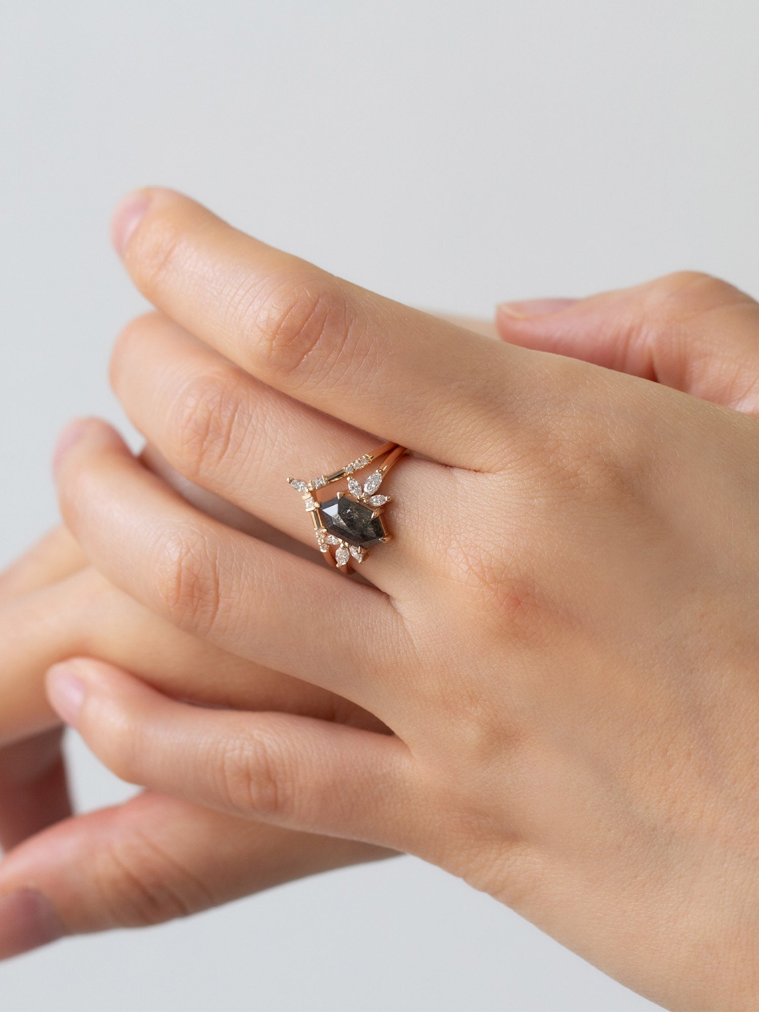 Art deco minimalistic hexagon salt and pepper diamond engagement ring in 14k rose gold with six smaller marquise diamonds on model'shand.