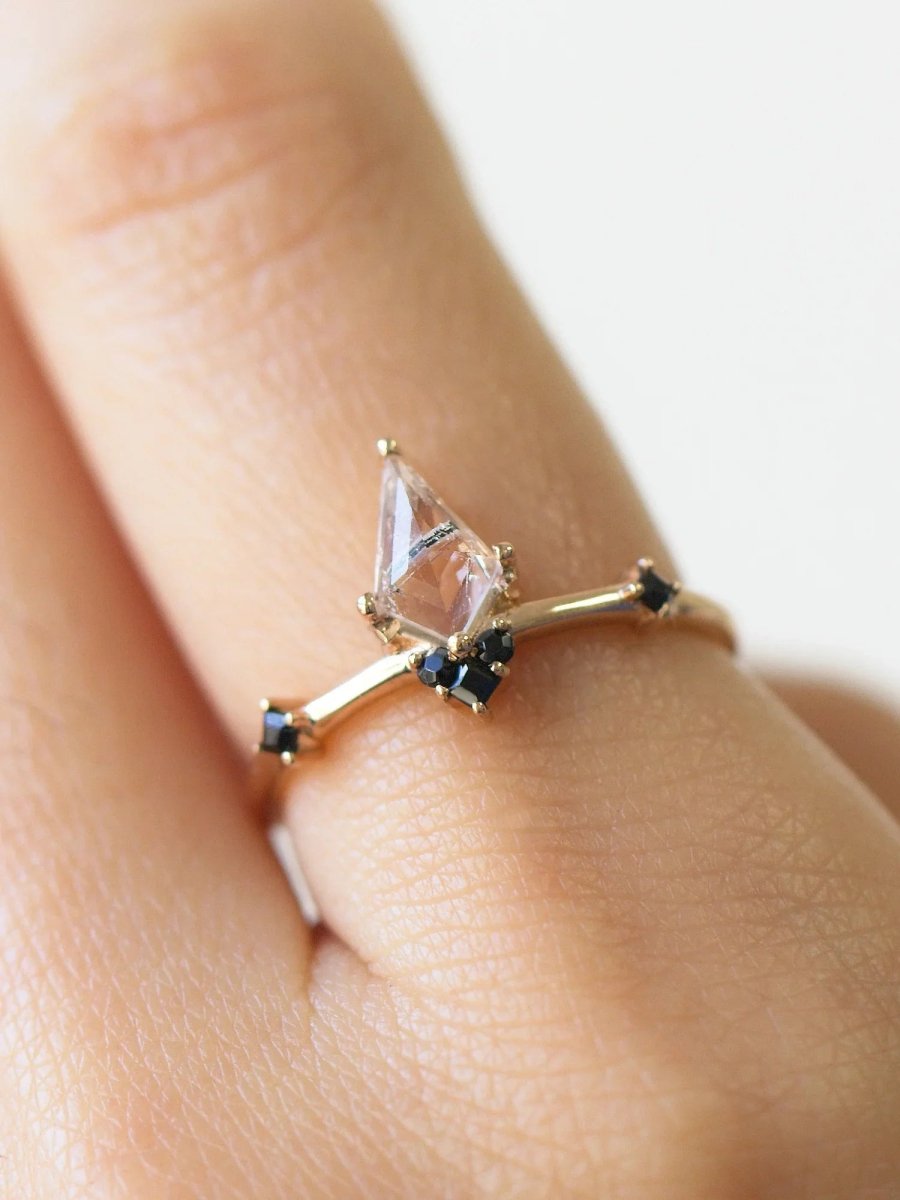 Close-up of finger wearing minimalist Art Deco ring with kite tourmalinated center and onyx accents, highlighting fine details