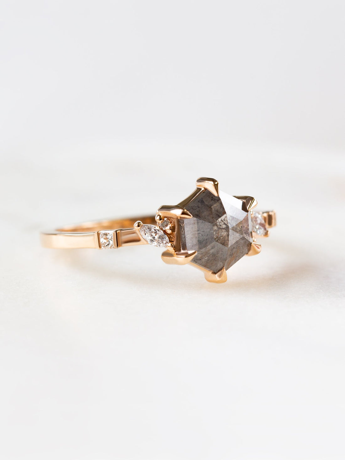 Unique art deco styled hexagon shaped salt and pepper diamond engagement ring in 14k rose gold with smaller marquise, round, and princess cut diamonds.