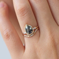 Pear-shaped salt and pepper diamond engagement ring in 14k rose gold inspired by the art deco style and minimalism on model's hand.