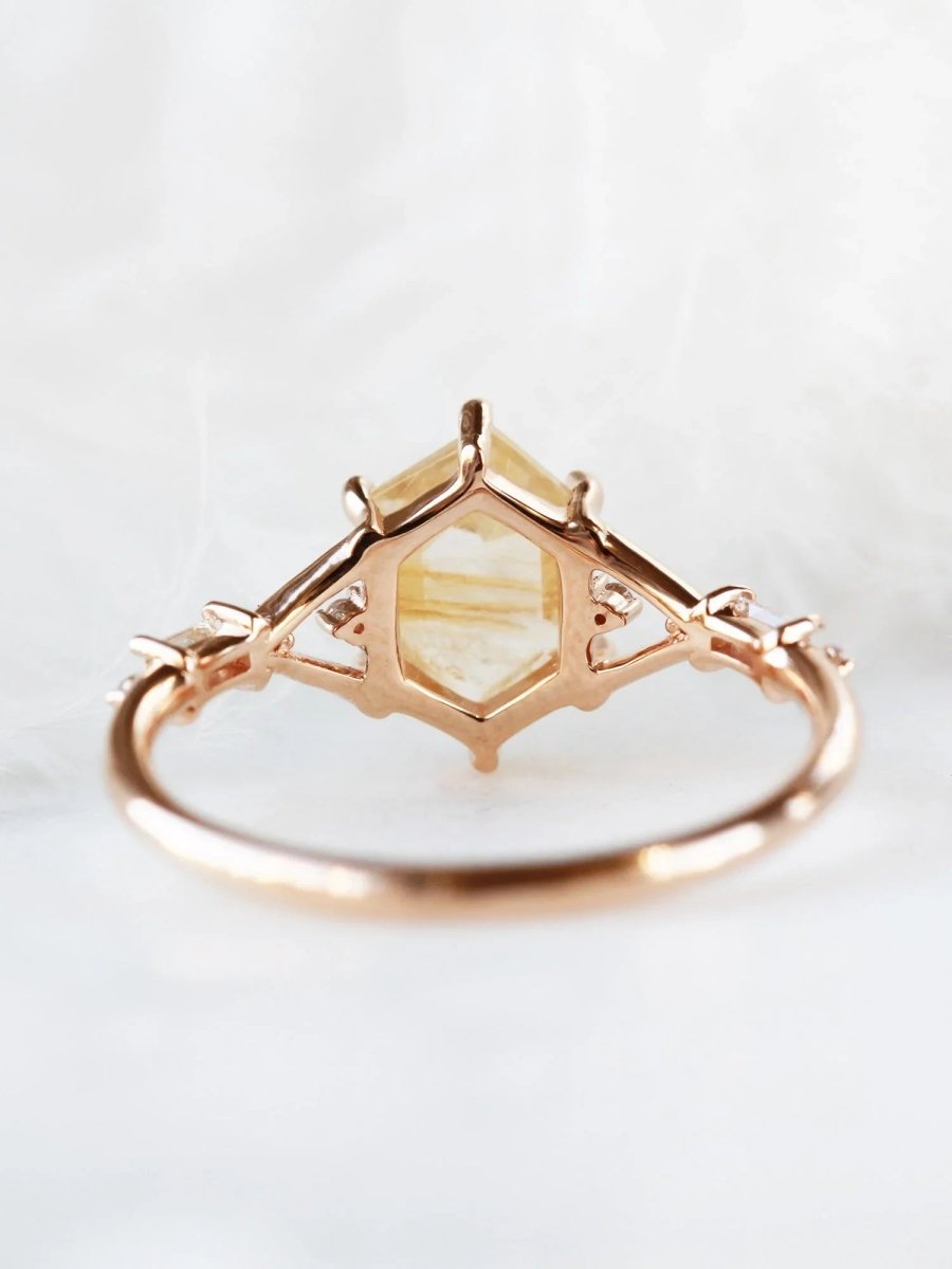 Hexagon rutilated quartz engagement ring in 14k rose gold with smaller baguette and round diamonds inspired by the art deco style and minimalism.
