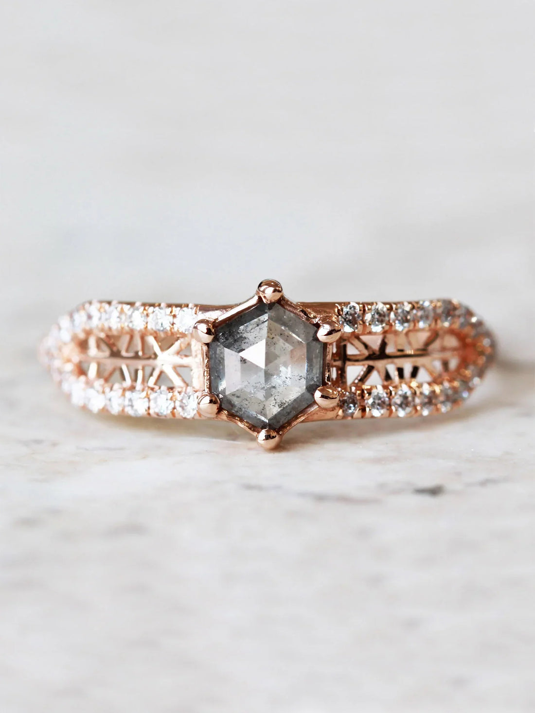 Face view of contemporary engagement ring in sunlight, highlighting the salt pepper diamond’s brilliance and the sparkle of pave melee