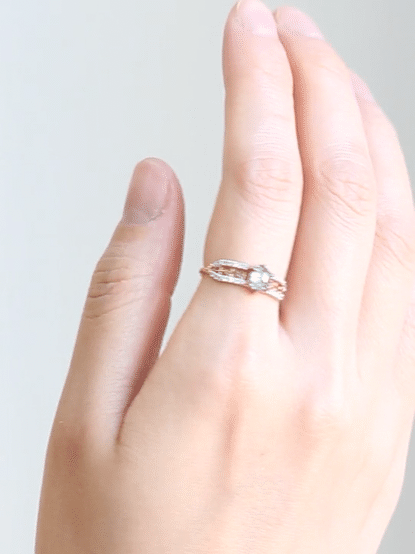 GIF of hand slowly turning, wearing contemporary engagement ring, showcasing the brilliance of the salt pepper diamond and sparkle of the pave