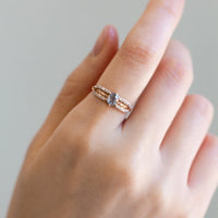 Relaxed hand wearing contemporary engagement ring on index finger, captured in soft natural lighting to highlight the salt pepper diamond and pave sparkle