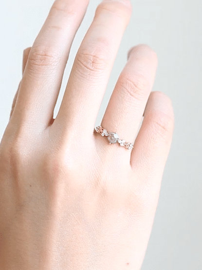 GIF of a hand wearing a petite Modern Art Deco ring with a salt and pepper center stone, trefoil clusters, and intricate latticework