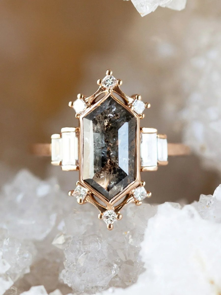 Rose gold ring with a large central gemstone and smaller diamonds on a textured stone background