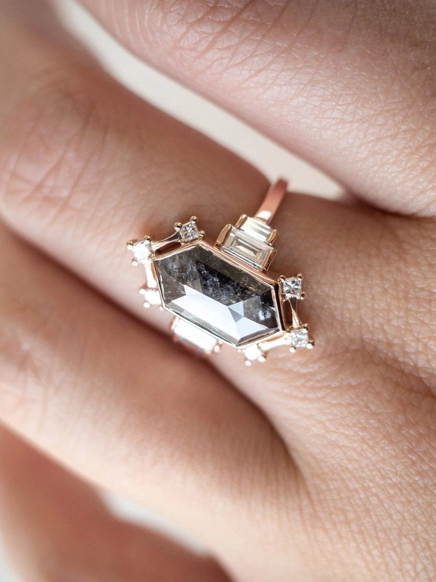 Rose gold ring with a large gemstone and smaller diamonds on a finger