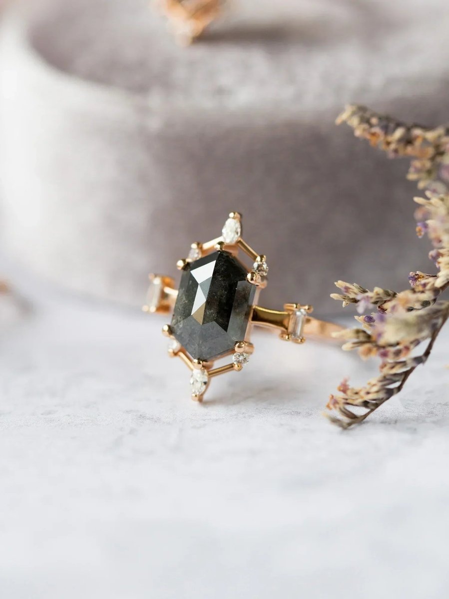 a contemporary Art Deco ring with hexagon center stone, semi-halo detail on fabric with leaves