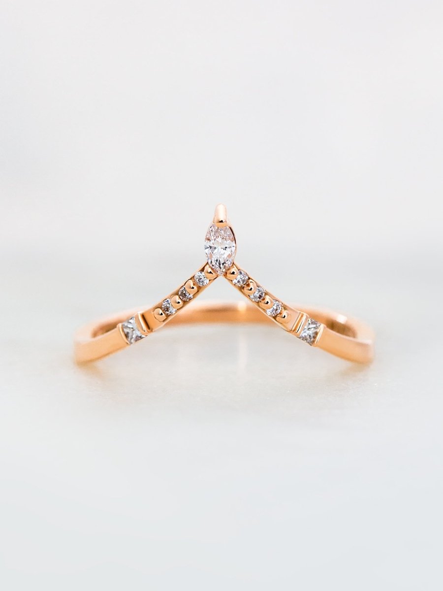 A rose gold band ring with multiple smaller bands on either side, featuring clear gemstones.