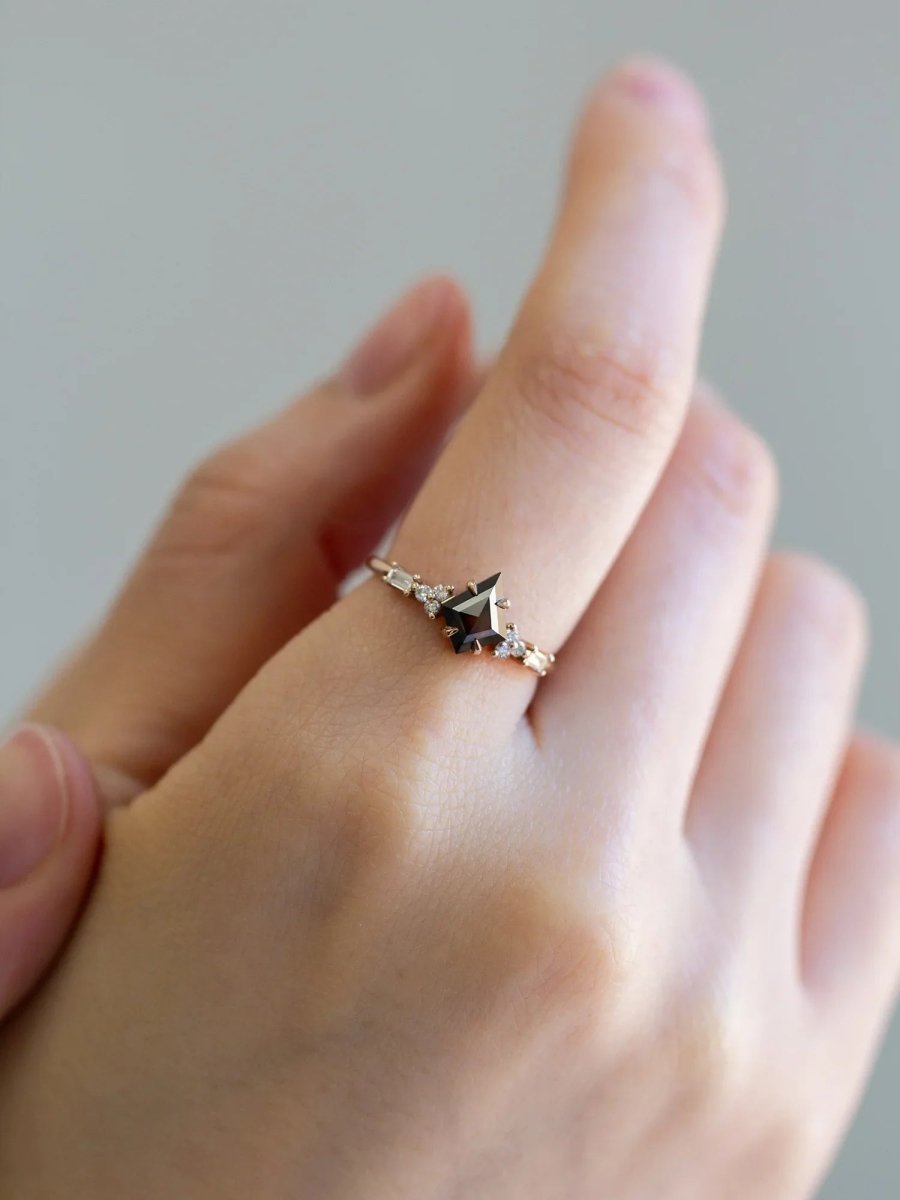 hand wearing petite ring with kite salt and pepper diamond, trefoil melee accents on shoulders, and baguette stones on band.