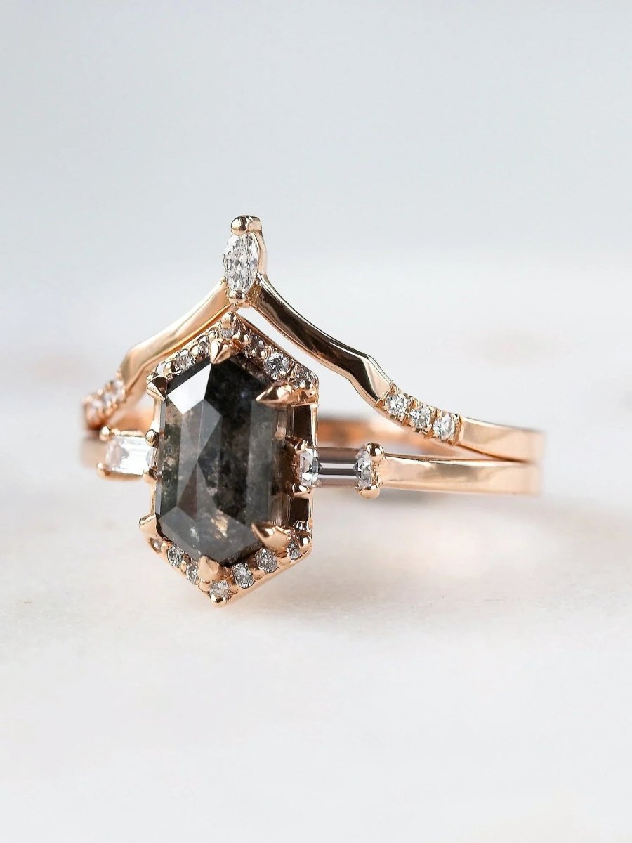 Rose gold ring with a large dark gemstone and smaller diamonds on a light background